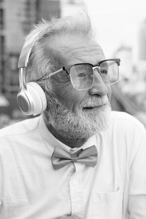 Handsome bearded senior tourist man exploring the city in black and whiteの写真素材