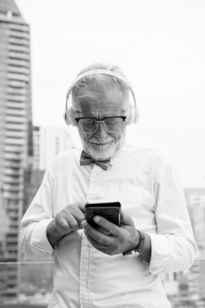 Handsome bearded senior tourist man exploring the city in black and whiteの写真素材