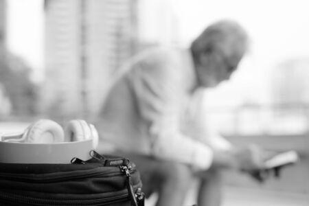 Handsome bearded senior tourist man exploring the city in black and whiteの写真素材