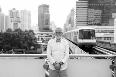 Handsome bearded senior tourist man exploring the city in black and white