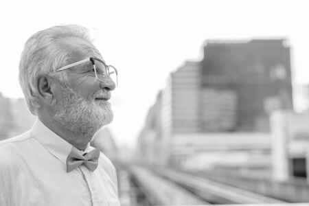 Handsome bearded senior tourist man exploring the city in black and whiteの写真素材