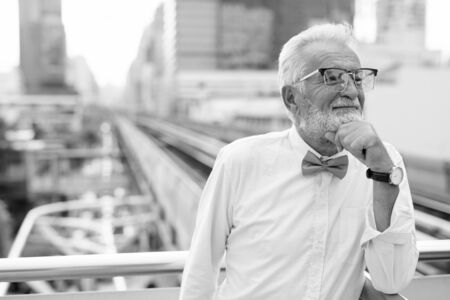 Handsome bearded senior tourist man exploring the city in black and whiteの写真素材
