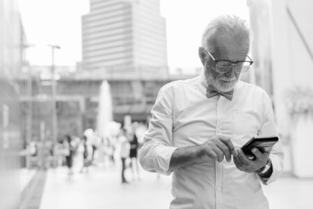 Handsome bearded senior tourist man exploring the city in black and whiteの写真素材