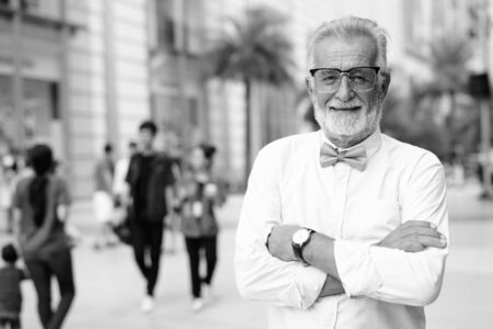 Handsome bearded senior tourist man exploring the city in black and white