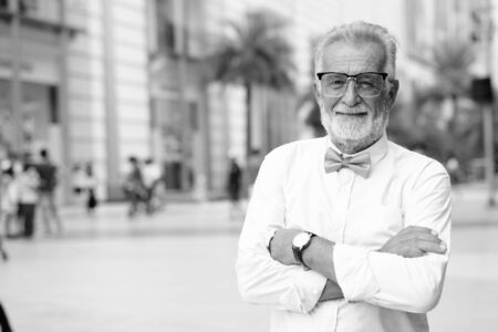Handsome bearded senior tourist man exploring the city in black and whiteの写真素材