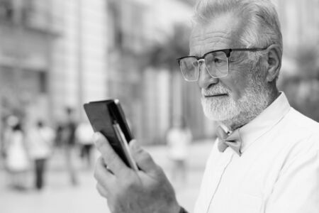 Handsome bearded senior tourist man exploring the city in black and whiteの写真素材