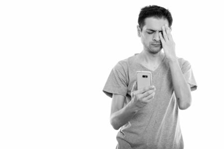 Studio shot of young man using mobile phone while looking stressedの写真素材
