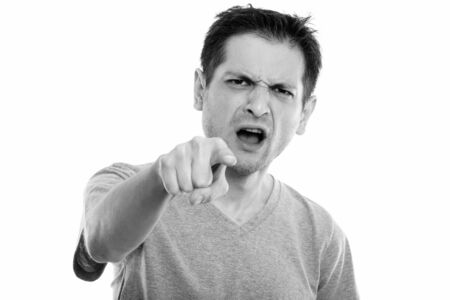 Studio shot of angry young man pointing at camera