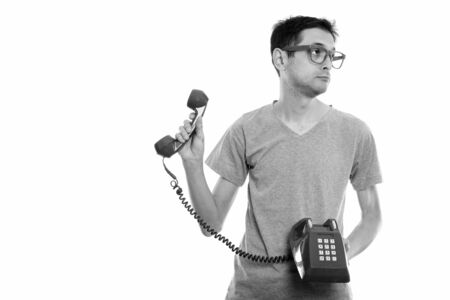 Studio shot of young man holding old telephone and looking awayの写真素材