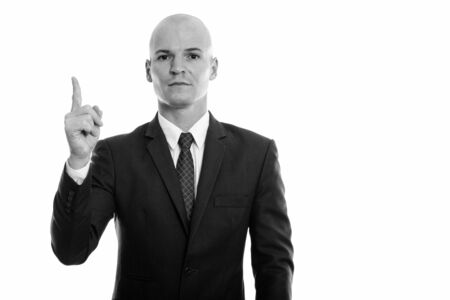 Studio shot of young handsome bald businessman pointing finger upの写真素材