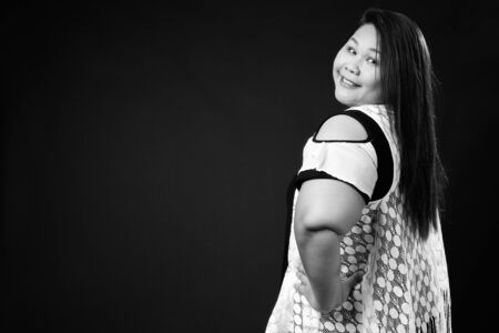 Beautiful overweight Asian woman against black background