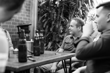 Group of men hanging out and relaxing together in the backyardの写真素材