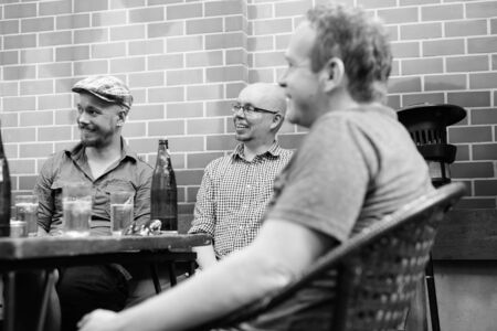 Group of men hanging out and relaxing together in the backyardの写真素材