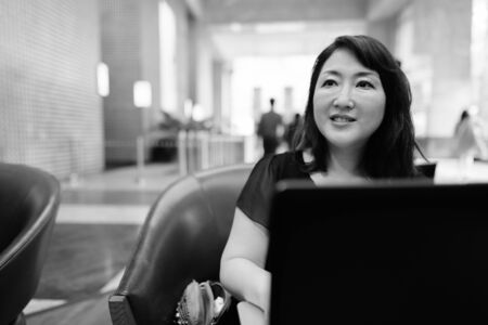 Mature beautiful Asian woman relaxing inside the coffee shopの写真素材