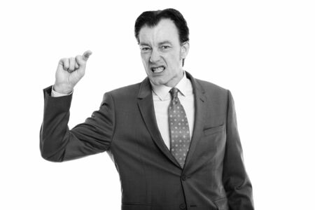 Studio shot of mature businessman looking furious while pointing fingerの写真素材