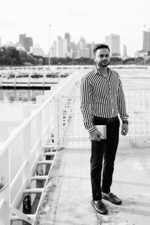 Young bearded Indian businessman relaxing at the park in the cityの写真素材