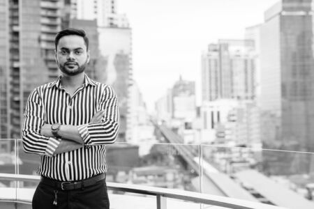 Young bearded Indian businessman against view of the cityの写真素材