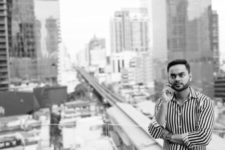 Young bearded Indian businessman against view of the city