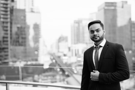 Young bearded Indian businessman against view of the cityの写真素材