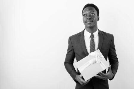 Young handsome African businessman holding gift box against white backgroundの写真素材