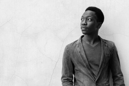 Young handsome African man wearing denim jacket against concrete wall outdoorsの写真素材