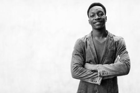 Young handsome African man wearing denim jacket against concrete wall outdoorsの写真素材