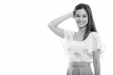 Studio shot of happy young beautiful woman smiling and brushing hair backの写真素材