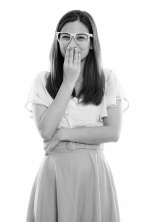 Studio shot of happy young beautiful woman smiling and giggling while covering mouthの写真素材