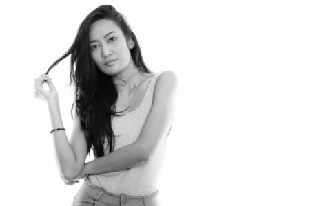 Studio shot of young beautiful Asian woman touching her hairの写真素材