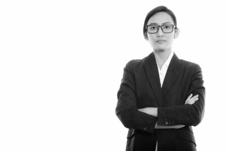 Studio shot of young Asian businesswoman wearing eyeglasses with arms crossedの写真素材