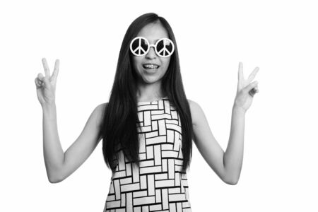 Young happy Asian teenage girl smiling while giving peace sign with both hands looking stylishの写真素材