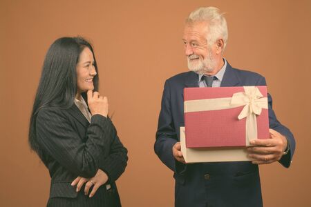 Mature multi-ethnic business couple against brown background