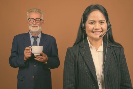 Mature multi-ethnic business couple against brown backgroundの写真素材