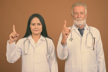 Mature multi-ethnic couple doctors against brown backgroundの写真素材