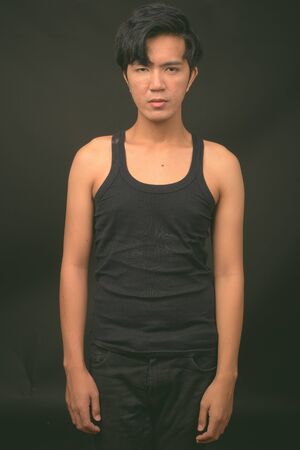 Young handsome Asian man against black backgroundの写真素材