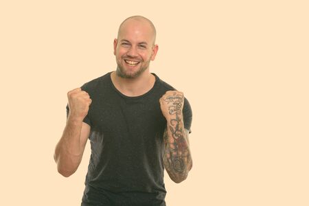 Studio shot of young happy bald muscular man smiling while looking excitedの写真素材
