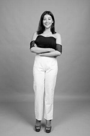 Young beautiful Asian woman against gray backgroundの写真素材