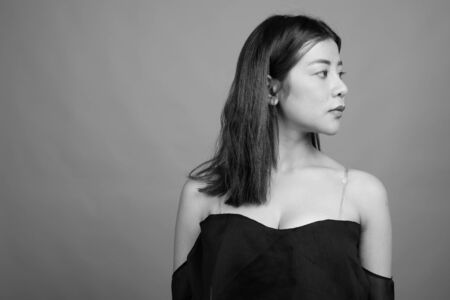 Young beautiful Asian woman against gray backgroundの写真素材