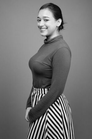 Young beautiful Indian woman against gray backgroundの写真素材