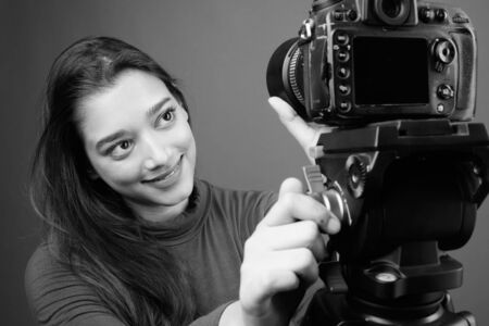 Young beautiful Indian woman vlogging against gray backgroundの写真素材