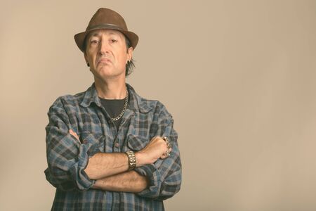 Studio shot of angry mature gangster man with arms crossedの写真素材