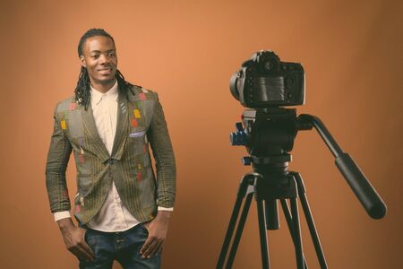 Young handsome African businessman against brown backgroundの写真素材