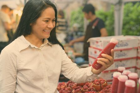 Mature Asian businesswoman shopping at the street marketの写真素材