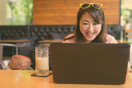 Mature Asian woman relaxing at coffee shopの写真素材