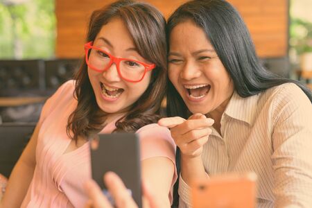 Two mature Asian women together hanging out at the coffee shopの写真素材