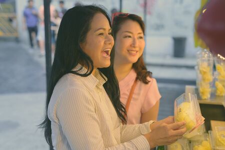 wo mature Asian women shopping together in the street marketの写真素材