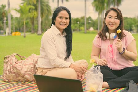 Two mature Asian women together relaxing at the parkの写真素材