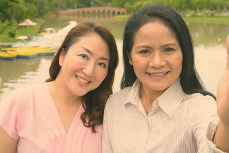 Two mature Asian women together relaxing at the parkの写真素材