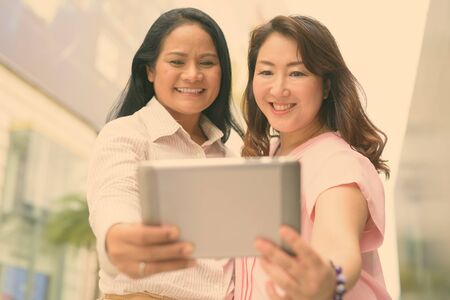 Two mature Asian women together outside the mall in Bangkok cityの写真素材
