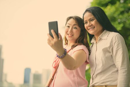 Two mature Asian women together against view of the cityの写真素材
